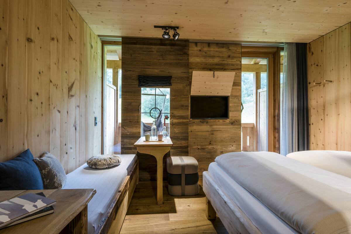 Una habitación de cabaña de madera con dos camas, una mesita y una ventana.