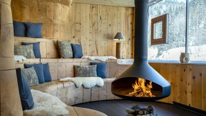 A cozy cabin interior with a built-in fireplace, wooden walls, and a comfortable seating area. - mama thresl (Leogang)