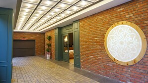 Un couloir doté d’un sol carrelé, d’un mur en briques et d’un plafond avec des spots encastrés.