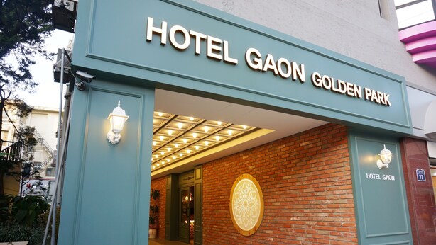 L’entrée de l’hôtel Gaon Golden Park, avec sa façade en briques et son enseigne lumineuse.