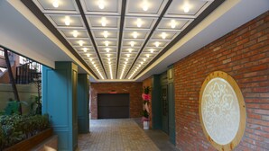 Un couloir doté d’un sol carrelé, d’un mur en briques agrémenté d’un panneau en bois décoratif et d’une porte au fond.