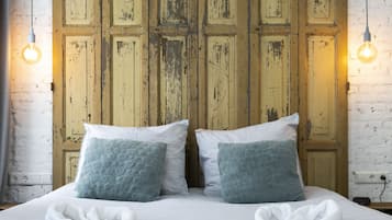 A bed with white linens, two pillows, and two white towels.