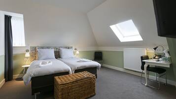 Un dormitorio con cama, escritorio, silla, lámpara, ventana y tragaluz.