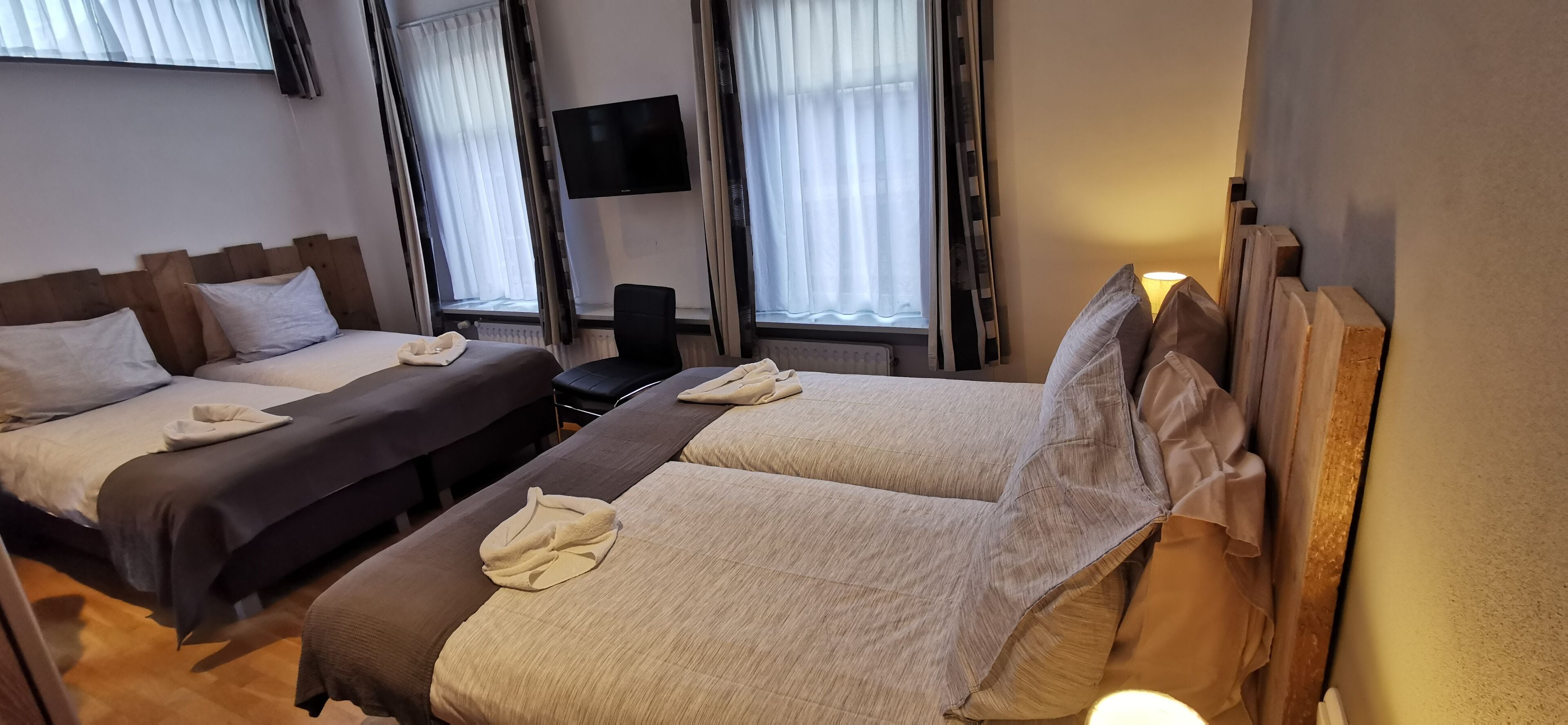 Habitación de hotel con dos camas, un televisor de pantalla plana y una silla.