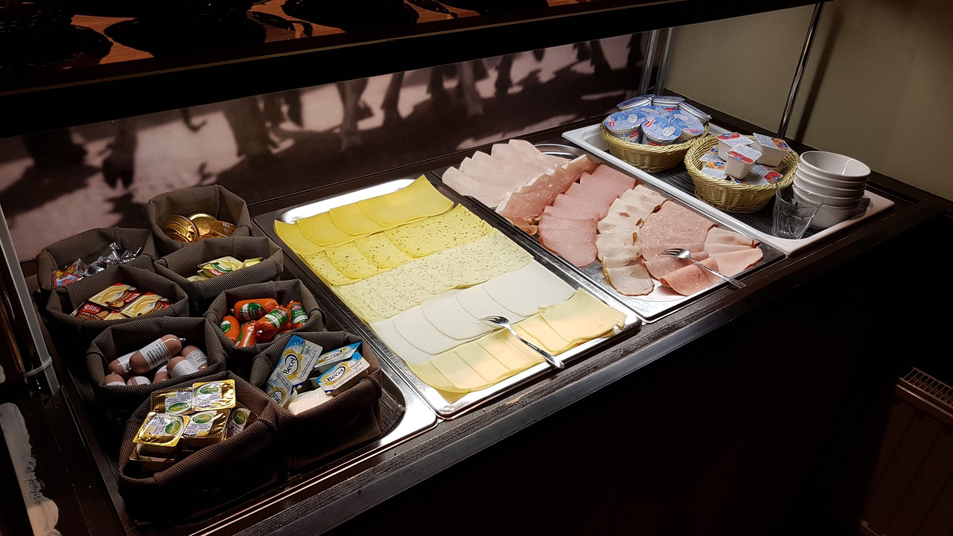Eine Feinkosttheke mit verschiedenen Fleisch- und Käsesorten sowie Beilagen.