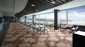 Un vaste espace dédié à la salle à manger, agrémenté d’un tapis à motifs, de grandes fenêtres offrant une vue sur l’extérieur et d’un design moderne au niveau du plafond.