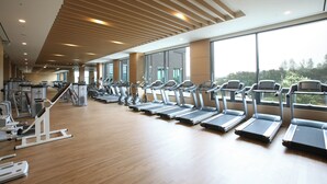 Une salle de sport équipée de tapis de course, de vélos elliptiques et d’autres appareils de musculation.