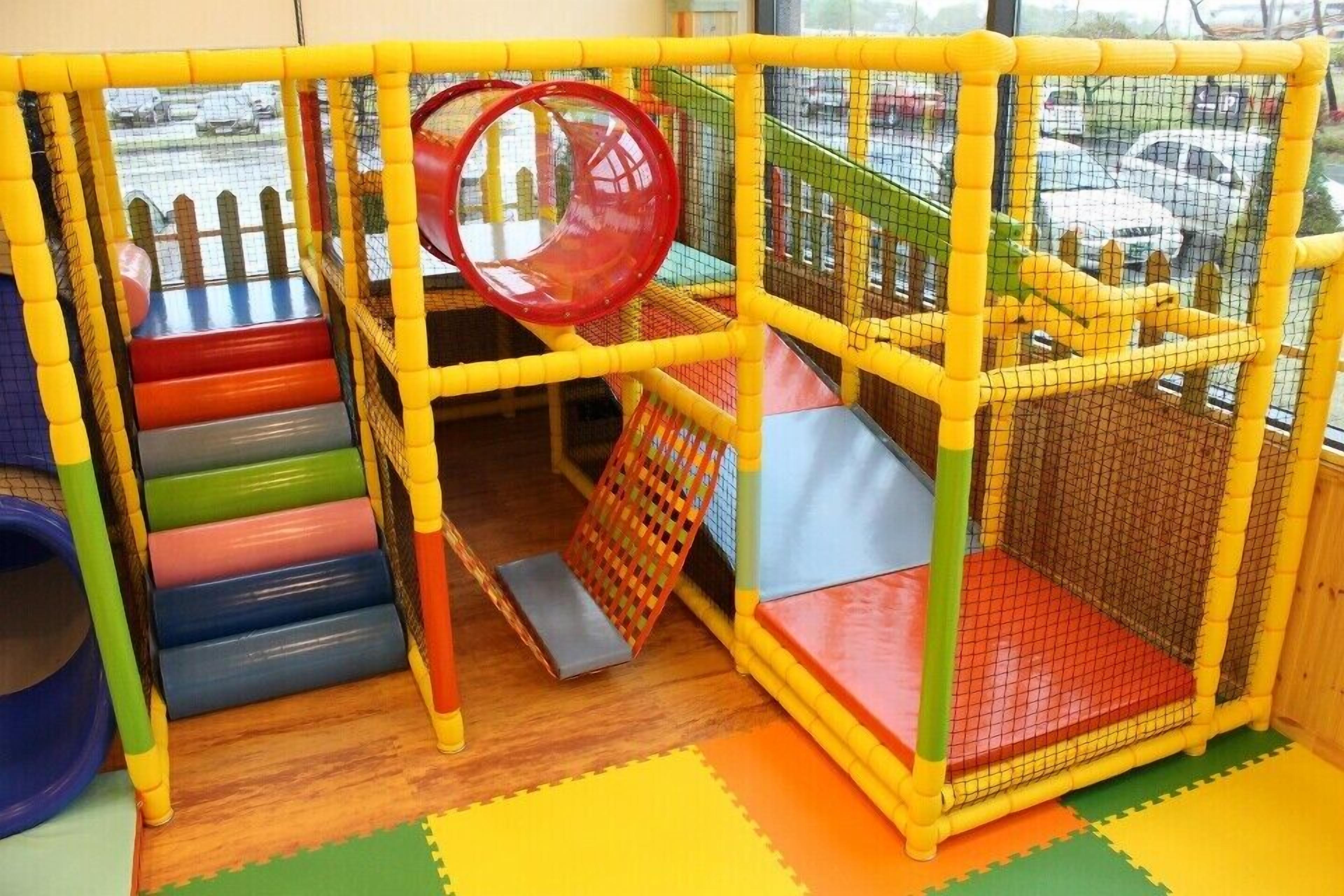 Ein Spielbereich mit Rutsche, Ballbecken und Netzumrandung.