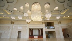 Un hall d’entrée spacieux, agrémenté d’un imposant lustre, d’un comptoir de réception et d’un grand motif décoratif sur le sol.
