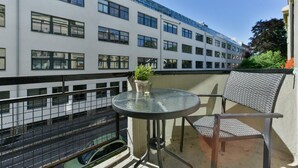 A balcony with a round table and a chair, a potted plant, and a view of a white building with multiple windows. - Forenom Serviced Apartments Oslo Rosenborg (Oslo)