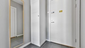 A hallway with a large mirror, a white door with a sticker, and grey tiled flooring. - Forenom Serviced Apartments Oslo Rosenborg (Oslo)