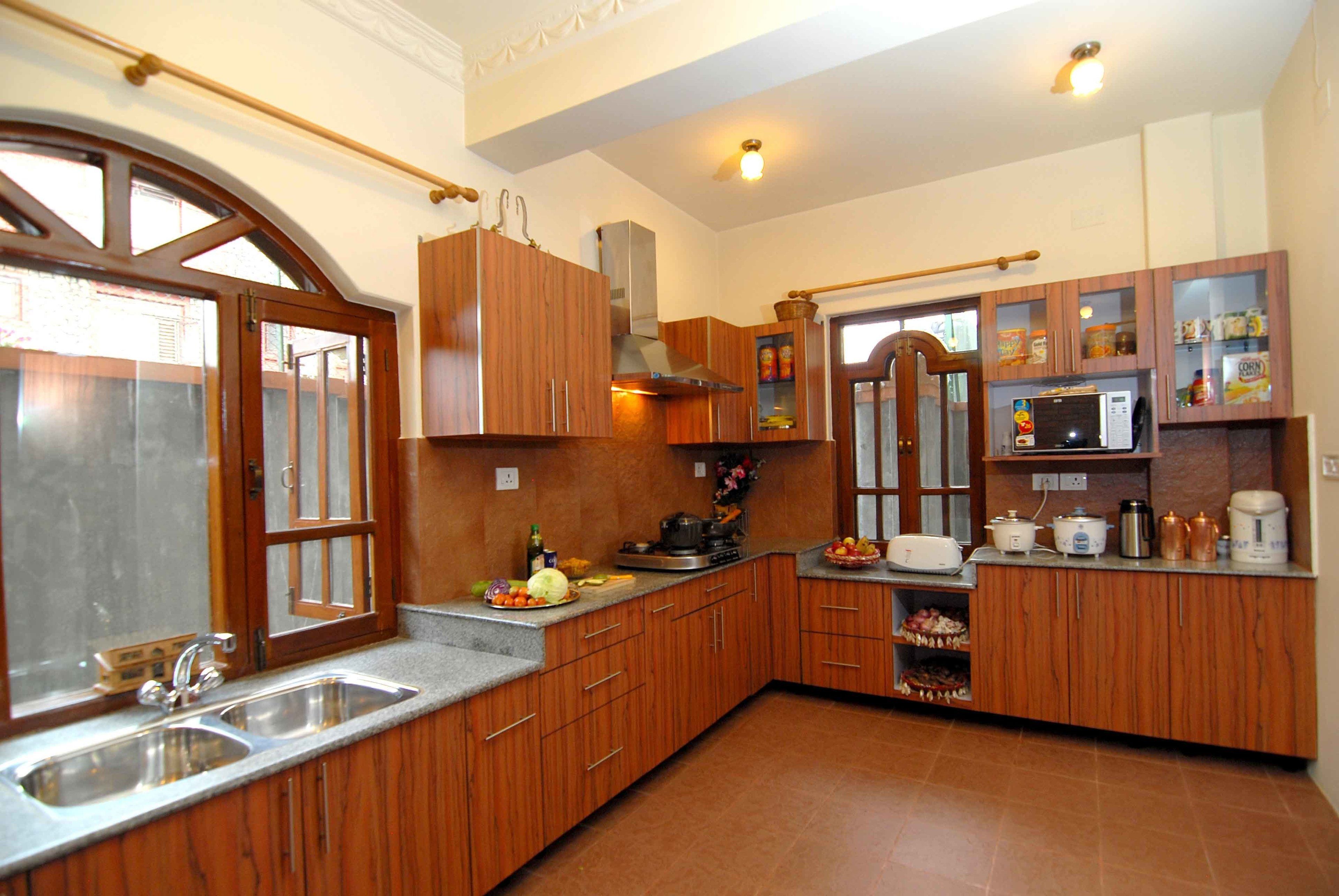 Cozinha com armários de madeira, pia dupla e diversos eletrodomésticos, incluindo micro-ondas e cafeteira.