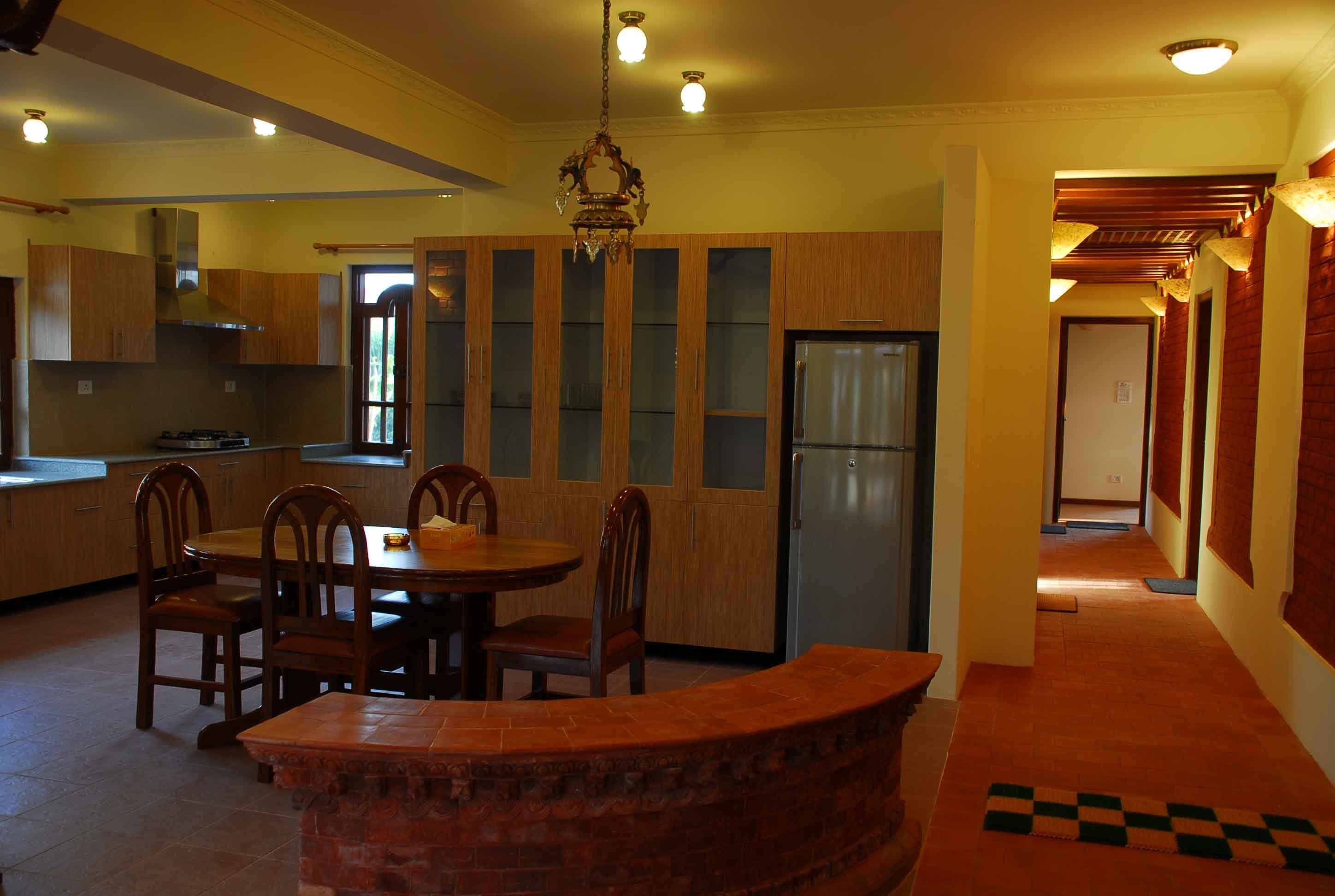 A kitchen with wooden cabinets, a dining table with chairs, a chandelier, and a refrigerator.