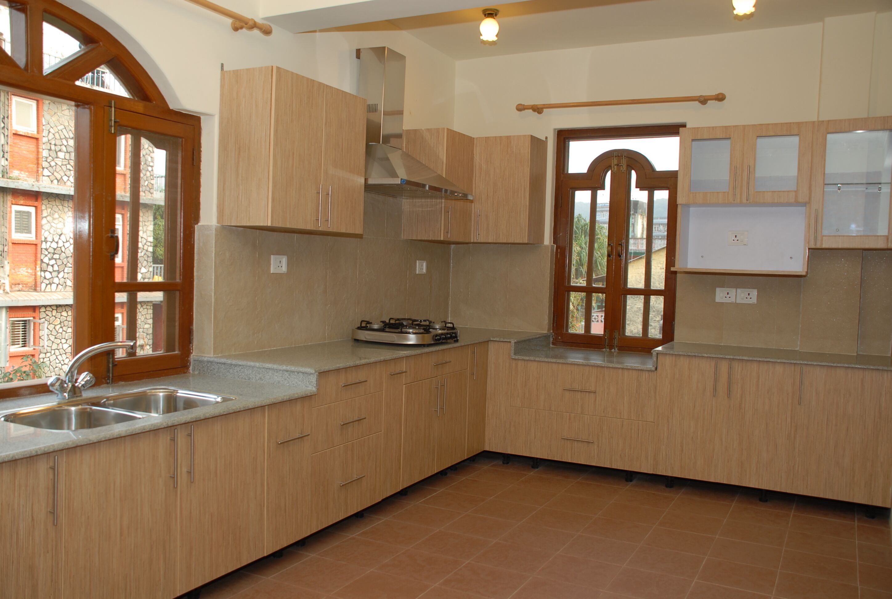 A kitchen with wooden cabinets, a gas stove, and a window with a view of buildings.