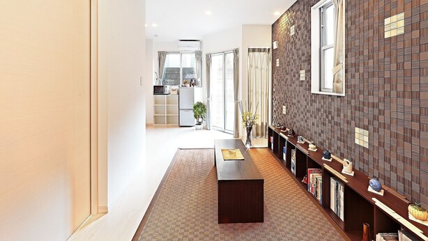 Un interior moderno con piso de madera, pared oscura con estampado y una estantería con diversos objetos.