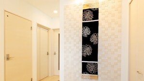 Un pasillo con puertas de madera, piso de baldosas y un panel decorativo con diseños florales.
