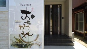 Un letrero de bienvenida con caracteres japoneses y el nombre 'Ochihara Guesthouse' en inglés.