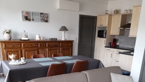 A modern living room with a sofa, dining table, and kitchen area.