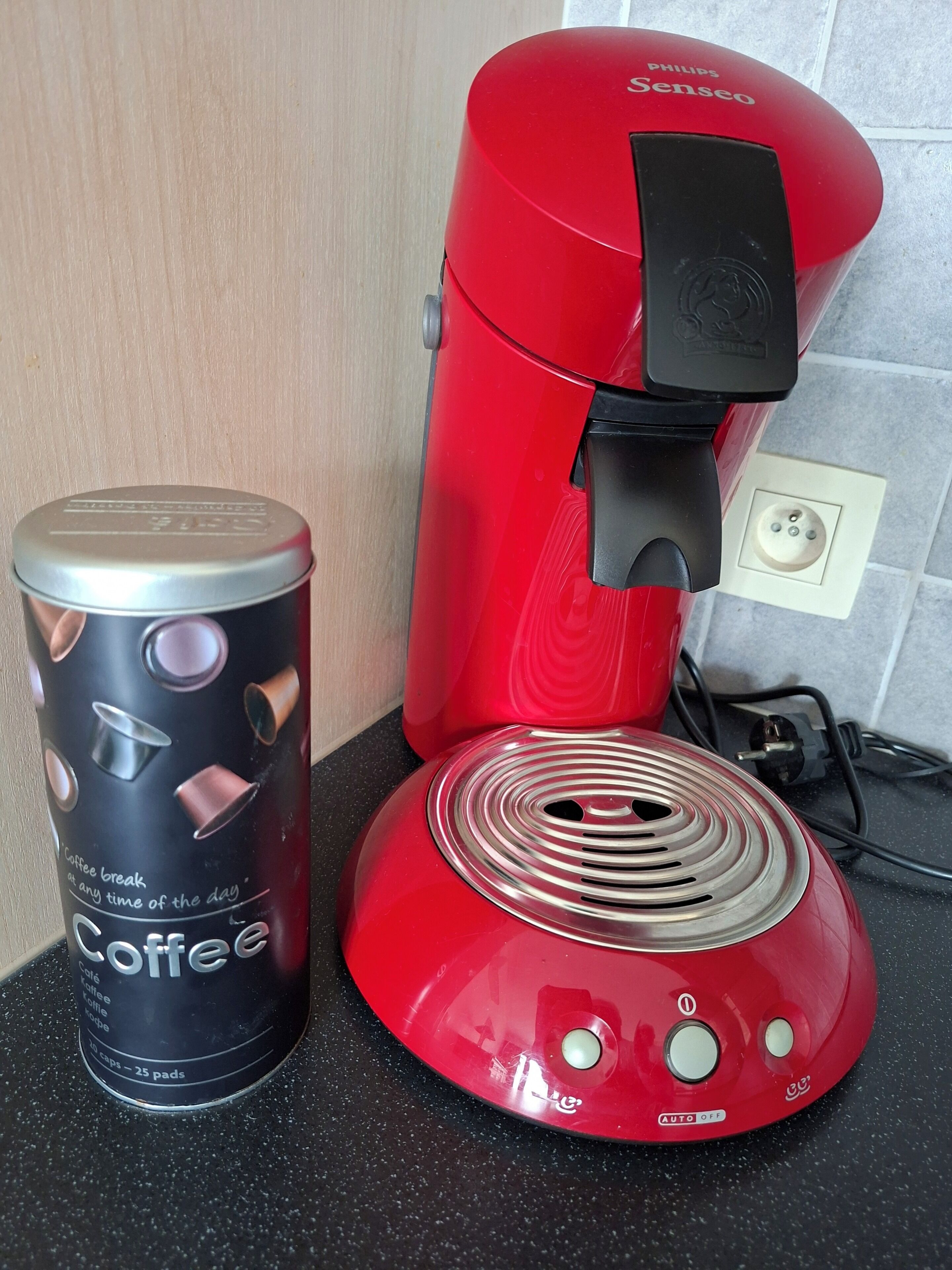 A red coffee maker and a canister labeled 'Coffee break at any time of the day' on a countertop.