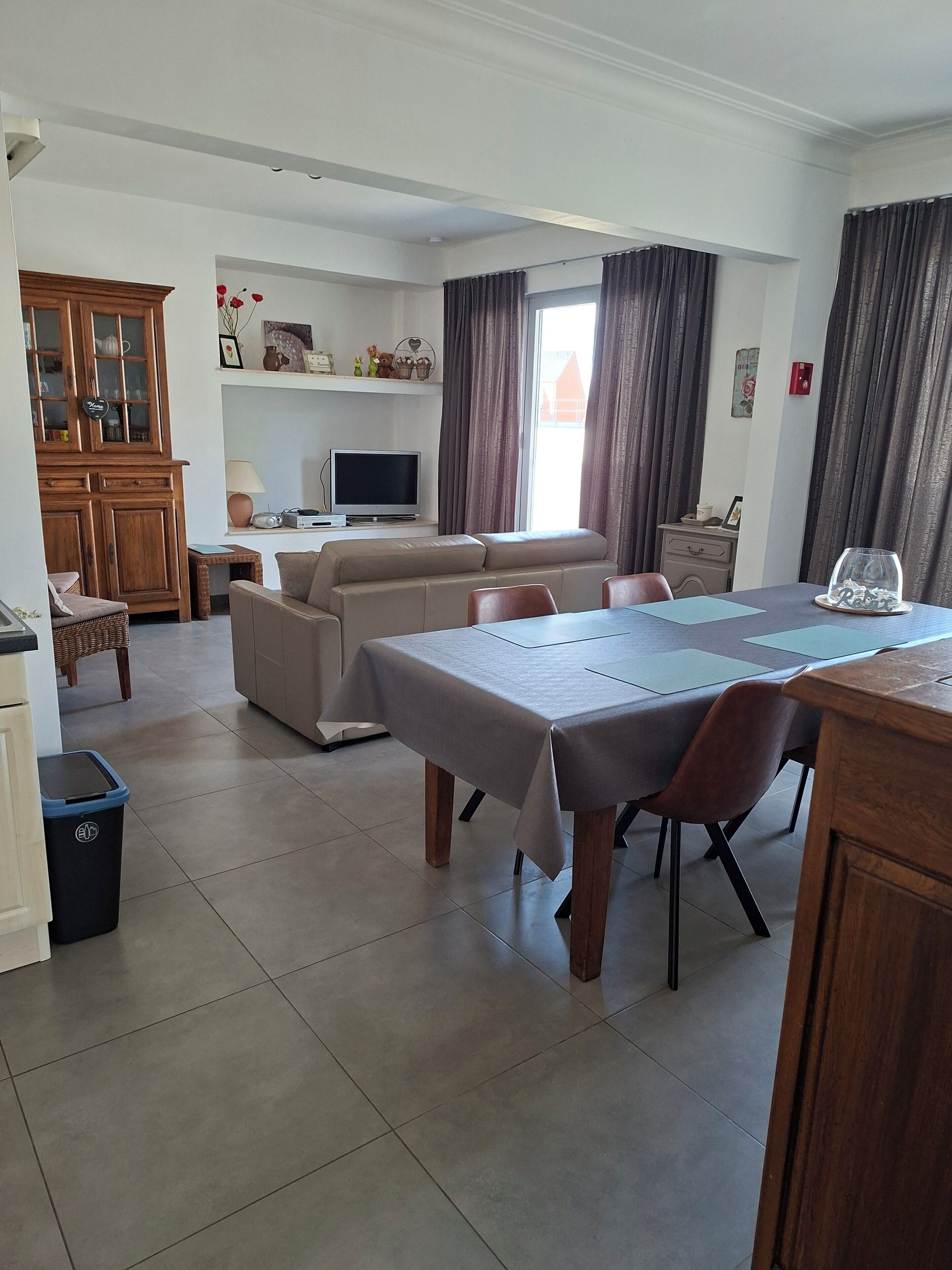 A spacious living area with a dining table, sofa, and television.