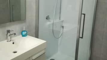 Une salle de bain moderne avec une douche à parois de verre, un lavabo blanc et un miroir au-dessus.