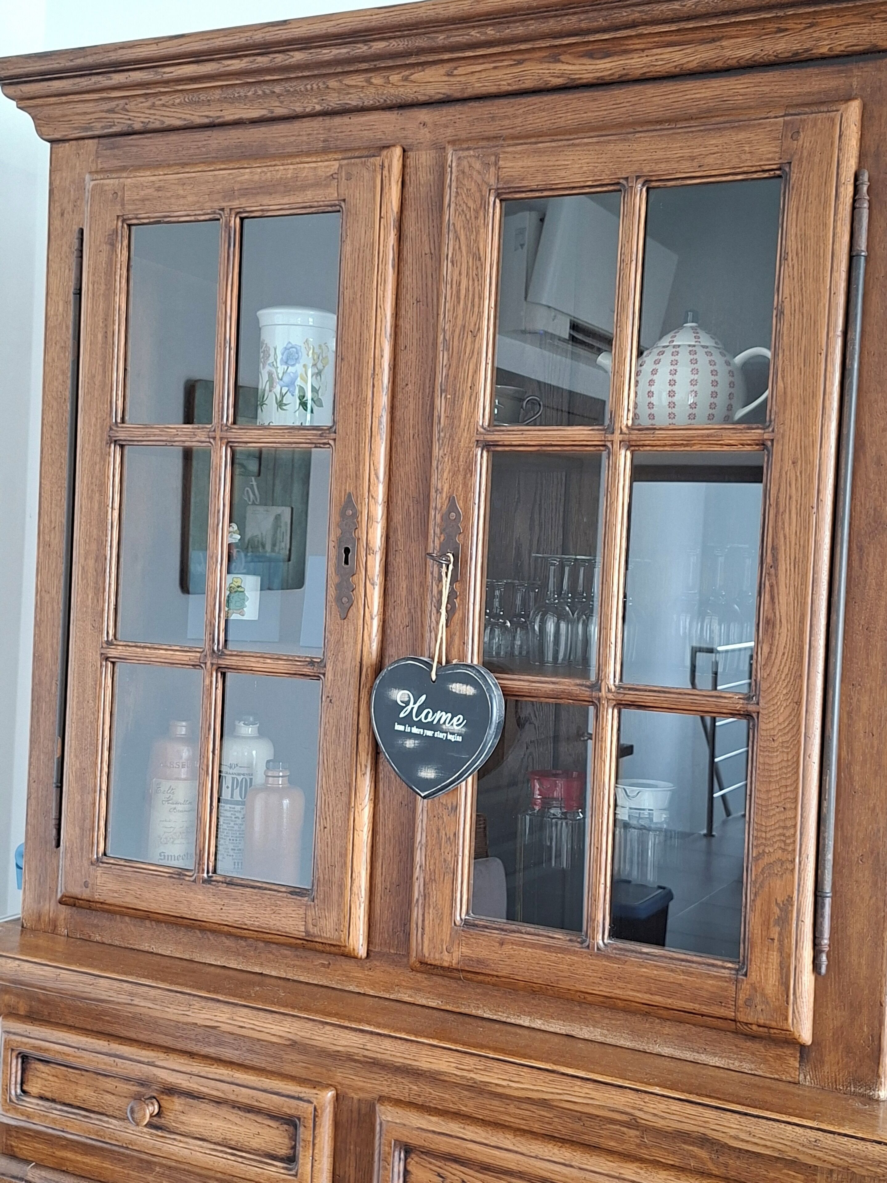 Un mobile in legno con ante in vetro, contenente diversi oggetti da cucina.