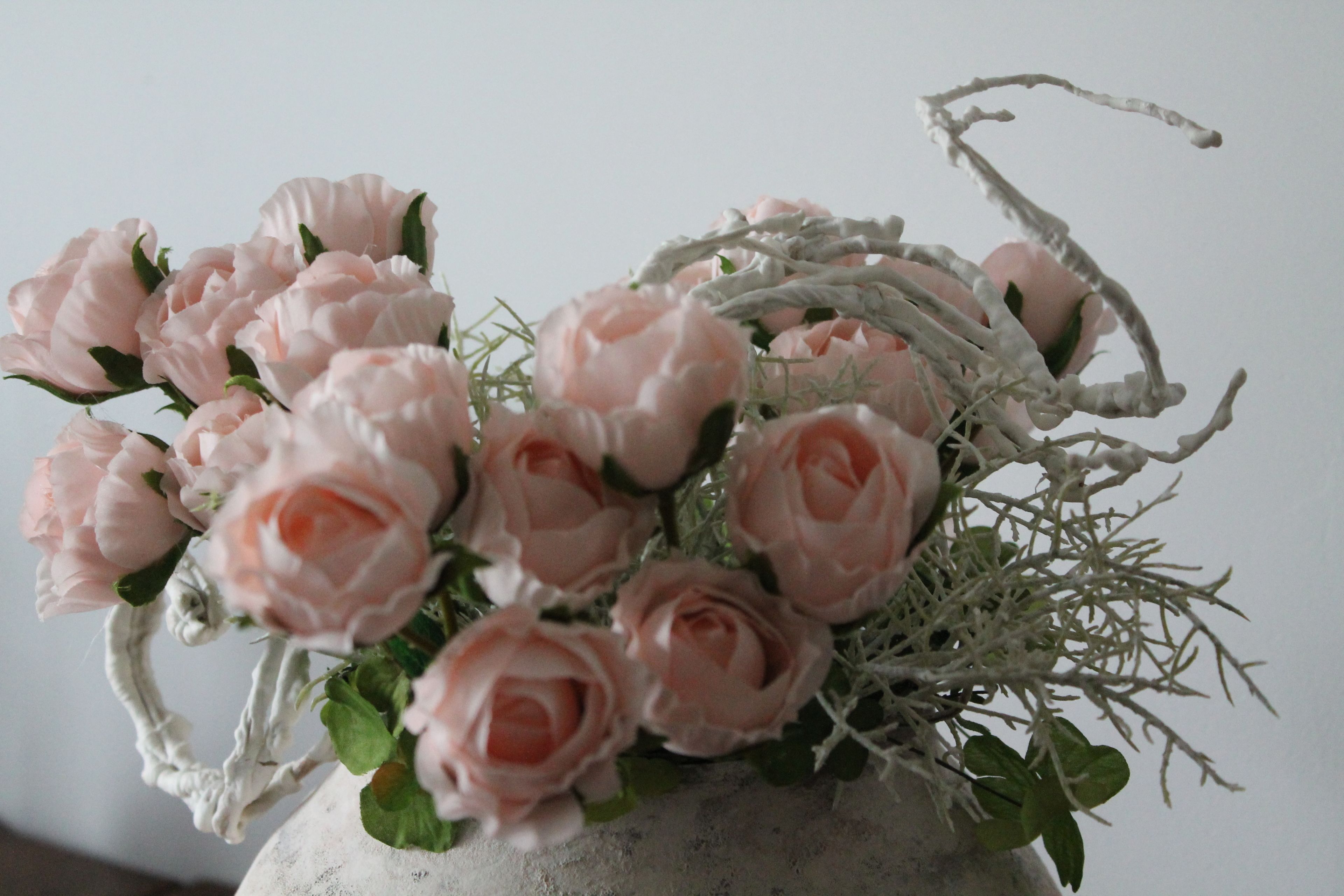 A bouquet of pink roses in a rustic vase.