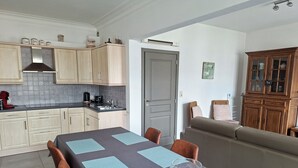 A modern kitchen with light wood cabinets, a built-in stove, and a coffee machine.