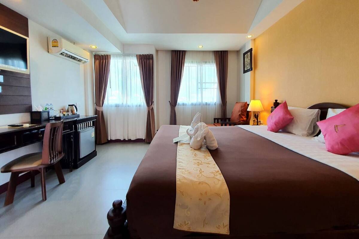 A hotel room with a bed, a desk, a chair, a lamp, and a picture on the wall.
