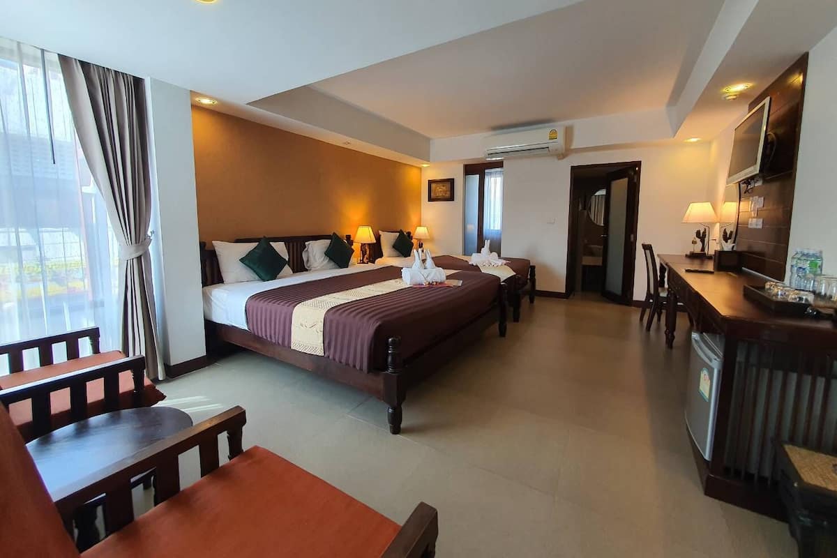 A hotel room with a large bed, a desk, and a dining area.
