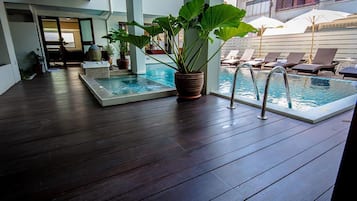 A pool area with two separate pools, lounge chairs, and potted plants.