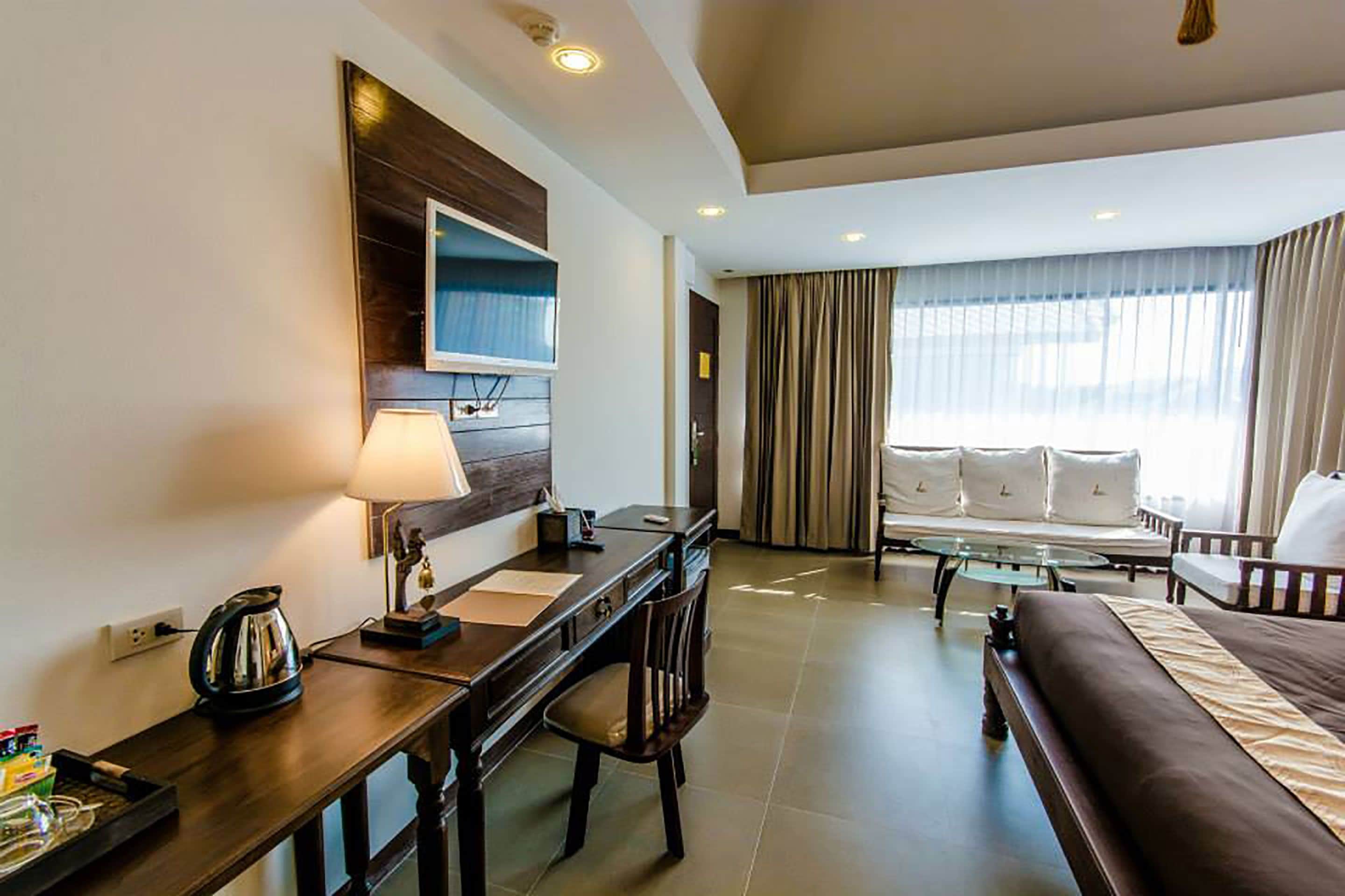 Quarto de hotel com escrivaninha, cadeira, cama e sofá.