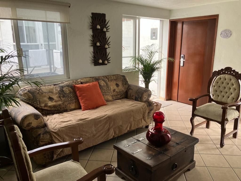 A living room with a sofa, two armchairs, a coffee table, and a door.
