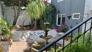 A courtyard with a fountain, potted plants, and a staircase. - Residencia Sofía (Querétaro)