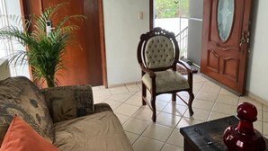A living room with a sofa, a chair, a potted plant, and a door. - Residencia Sofía (Querétaro)