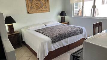 Une chambre à coucher avec un lit, deux tables de chevet avec des lampes, une décoration murale et une fenêtre avec des stores.