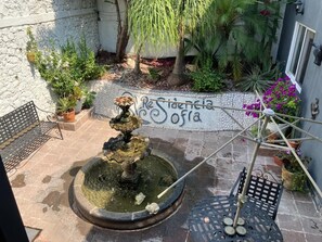 Un patio con una fuente, plantas en macetas y un muro con grafitis.