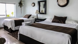 A hotel room with two beds, a window with a view of greenery, a mirror, and a wall-mounted decorative plate. - Residencia Sofía (Querétaro)