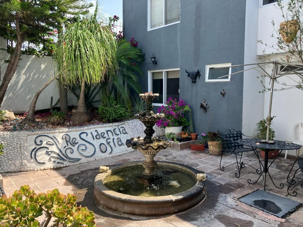 A courtyard with a fountain, potted plants, and a building with a sign reading "Residencia Sofía".