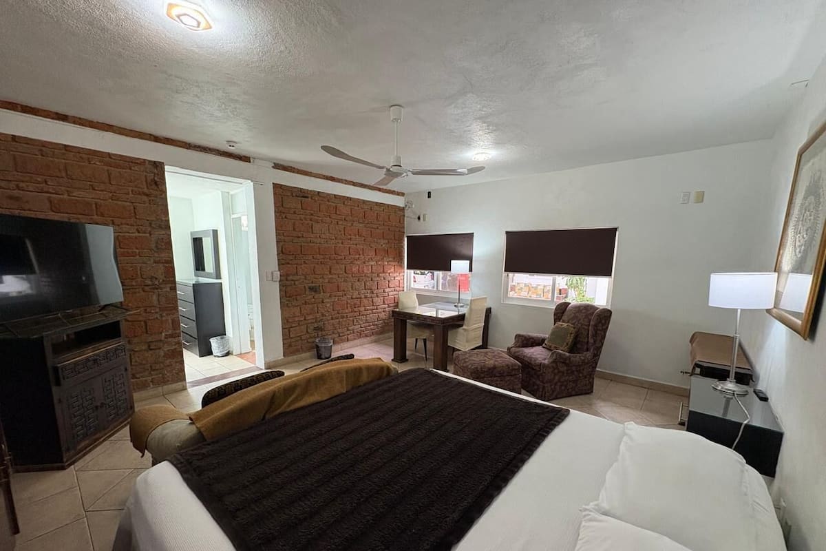 A hotel room with a large bed, a TV, a desk, and a chair.