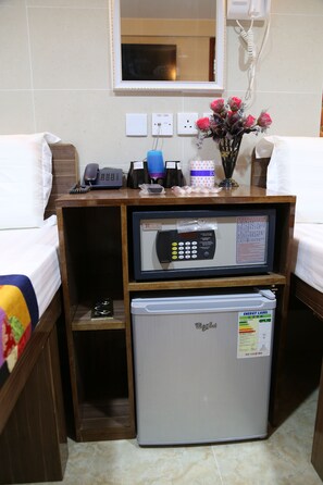 A hotel room with a minibar, a refrigerator, a telephone, and a mirror.