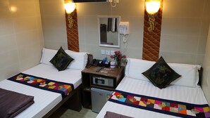 Une chambre d’hôtel avec deux lits, un petit bureau, un réfrigérateur et un climatiseur fixé au mur.