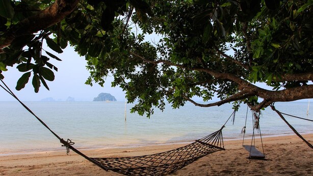 A hammock under a tree on a sandy beach with calm water and distant islands. - Thalane Resort (Krabi)