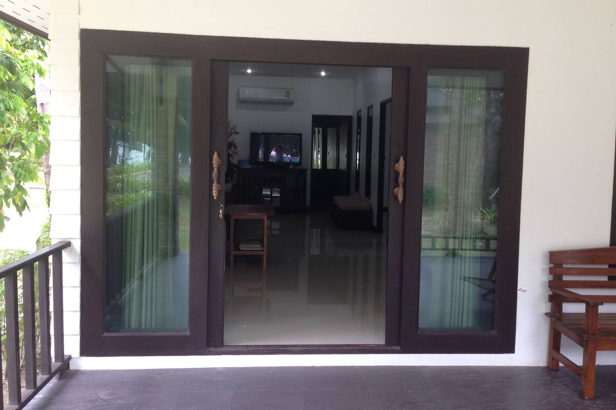 A sliding glass door entrance to a living area with a television, a bench, and a small table.