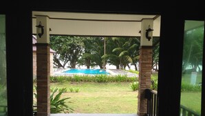 A covered outdoor area with a pool, surrounded by greenery and palm trees. - Thalane Resort (Krabi)