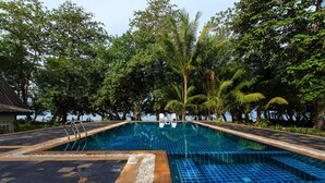 A rectangular swimming pool with a tiled edge, surrounded by pebbles and a wooden deck. - Thalane Resort (Krabi)