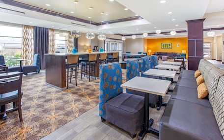 A hotel lobby with a reception desk, seating areas, and a patterned carpet.