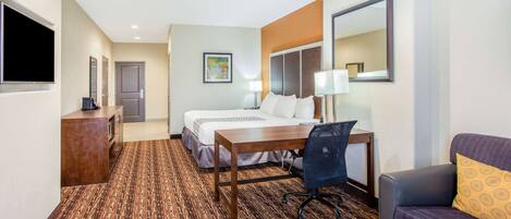 A hotel room with a bed, a desk, a chair, a sofa, a TV, and a mirror.