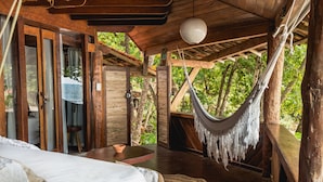 A wooden room with a bed, a hammock, and a view of the forest. - Pousada Sage Point (Itacaré)