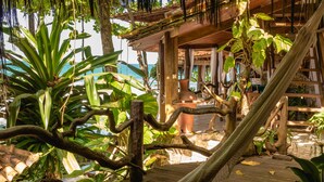 A wooden deck with a hammock, surrounded by tropical plants and a view of the ocean. - Pousada Sage Point (Itacaré)